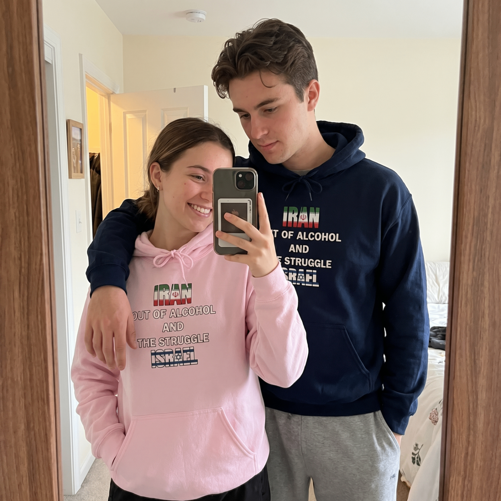 Customers wearing matching hoodie designs in a mirror selfie.